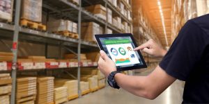 Worker hands holding tablet on blurred warehouse as background